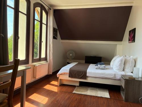 a bedroom with a bed and a desk and windows at LA CHERIELLE in Auvers-sur-Oise