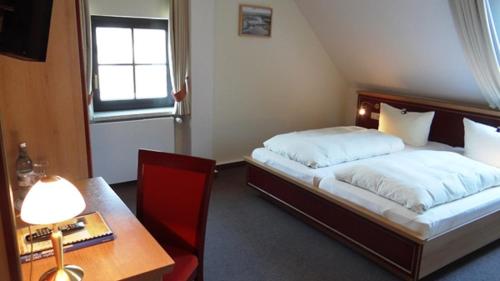 a bedroom with a bed and a table and a desk at Hotel und Restaurant Am Peenetal in Liepen