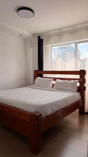 ein Schlafzimmer mit einem Holzbett und einem Fenster in der Unterkunft Bloomstays Furnished Apartments Nairobi - Two Bedroom With Sauna Gym & Workspace in Nairobi