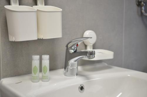 a bathroom sink with a faucet and two cups on it at Хотел КО НИ КО in Stara Zagora