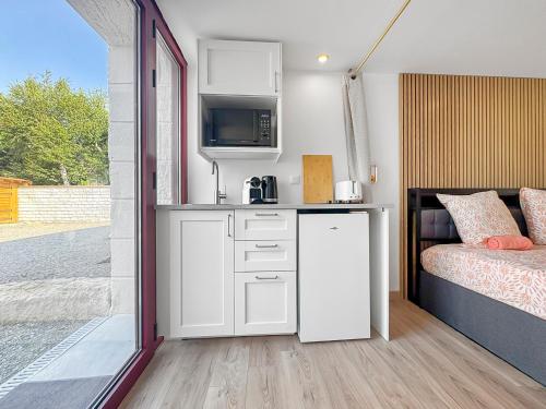 a room with a bed and a kitchen with a refrigerator at Les 4 AS de Jaunay, Intime, Jacuzzi in Jaunay-Clan