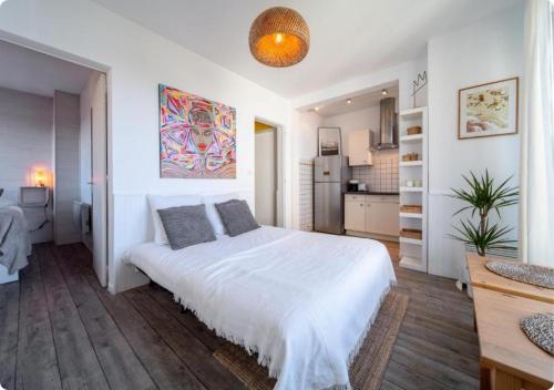 a bedroom with a white bed and a kitchen at Appartement à la Centrale avec vue Océan in Soorts-Hossegor
