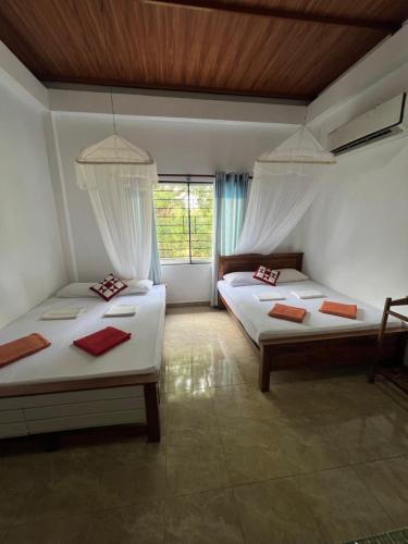 a bedroom with two beds and a window at Bungalow Resort - Sigiriya in Sigiriya