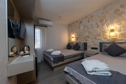 a bedroom with two beds and a stone wall at Nova Prime in Bodrum City