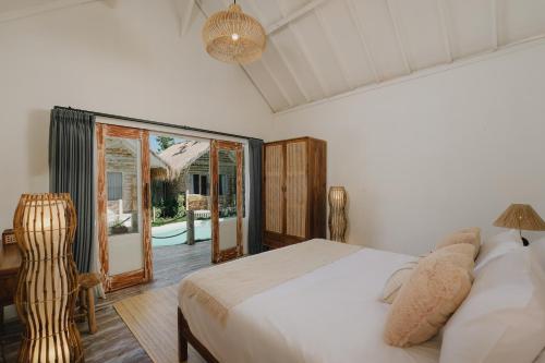 a bedroom with a bed and a sliding glass door at Tanahi Gili Air in Gili Islands