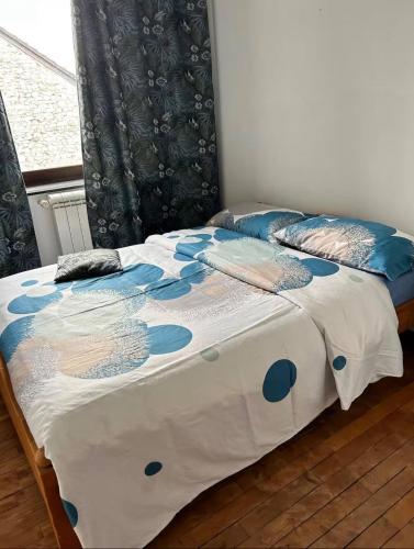 a bed with a blue and white comforter and a window at Private room with shared bathroom in Clavier