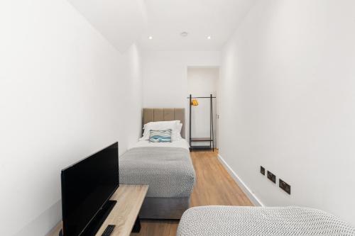 a bedroom with a bed and a flat screen tv at Bright 2BR Flat Close to Shops in Beckenham in Beckenham