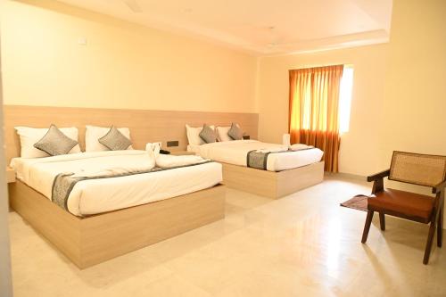 a hotel room with two beds and a chair at Hotel Siya Grand in Tirupati