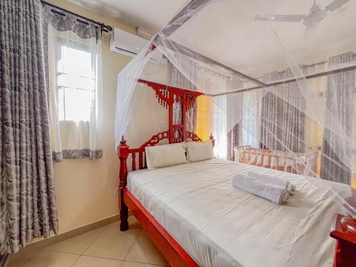 a bedroom with a red canopy bed with a window at Fiche Villas in Mombasa