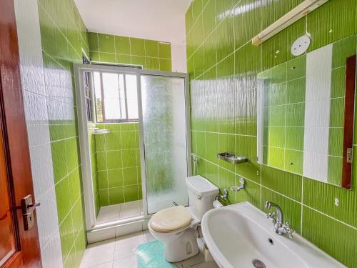 a green tiled bathroom with a toilet and a sink at Fiche Villas in Mombasa