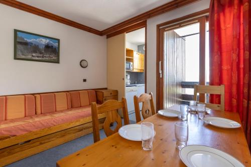 a dining room with a table and a couch at Résidence Odalys Le Hameau du Mottaret in Méribel