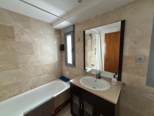 a bathroom with a sink and a tub and a mirror at Dumar Puerto Rey in Vera
