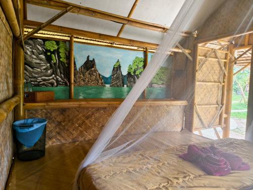 a bed in a room with a painting on the wall at Tarzan Bamboo hut in Khao Sok National Park