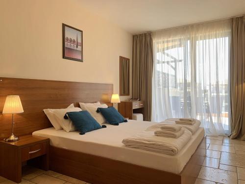 a bedroom with a large bed with blue pillows at Kaliakria Pearl Resort in Topola