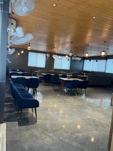 a dining room with tables and blue chairs at RS Galaxy Near AIMS Rishikesh in Rishīkesh