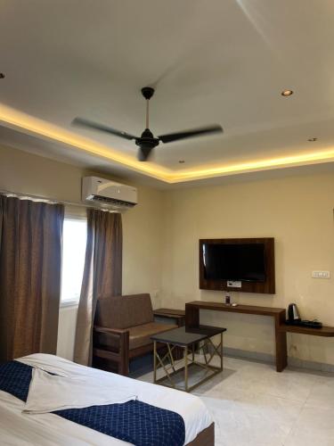 a hotel room with a bed and a flat screen tv at RS Galaxy Near AIMS Rishikesh in Rishīkesh