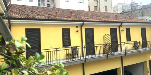a yellow building with black shutters on a balcony at Nextop Homes in Tortona