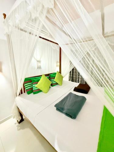 a white bed with green pillows in a room at Happy Night Holiday Inn in Unawatuna