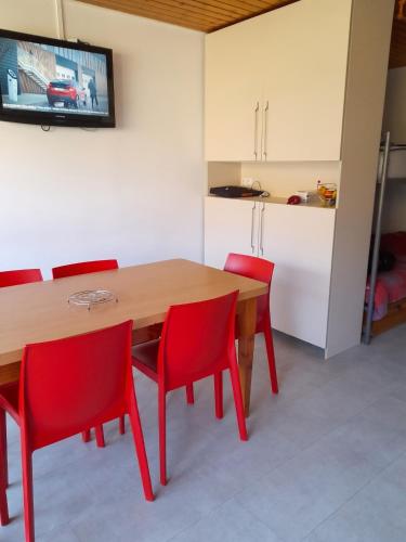 a dining room with a wooden table and red chairs at Studio accueillant à Les Carroz, 27 m², vue montagne in Les Carroz d'Araches