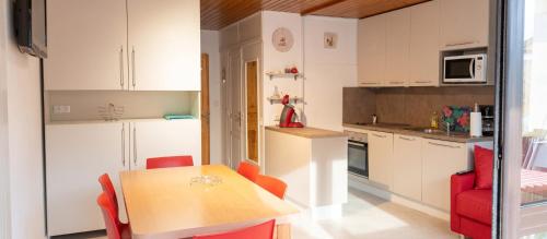 a kitchen with white cabinets and a table with red chairs at Studio accueillant à Les Carroz, 27 m², vue montagne in Les Carroz d'Araches