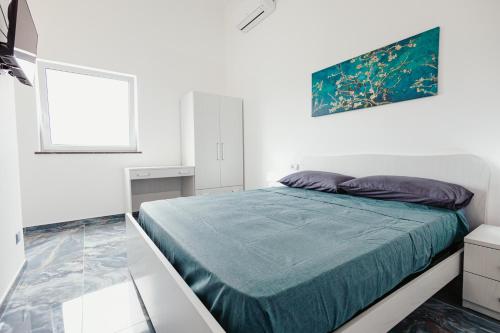 a white bedroom with a bed with a blue blanket at Tenuta Mari in Castelnuovo Cilento
