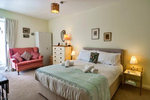 a bedroom with a large bed and a red chair at Finest Retreats - Curricle in Bideford