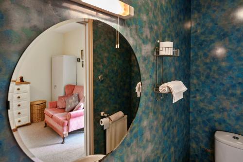 a bathroom with a mirror and a pink chair at Finest Retreats - Curricle in Bideford