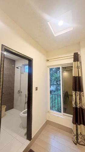 a bathroom with a shower and a toilet and a window at Shareef Lodge in Murree