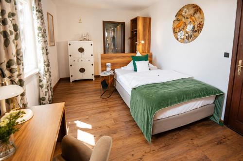 a bedroom with a bed with a green blanket on it at Hotel Vorderburg in Schlitz