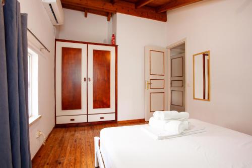 a bedroom with a bed with white sheets and wooden floors at Harmony House Corfu in Kynopiástai