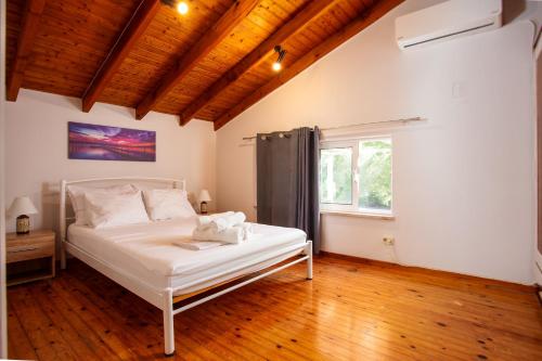 a bedroom with a white bed and a window at Harmony House Corfu in Kynopiástai