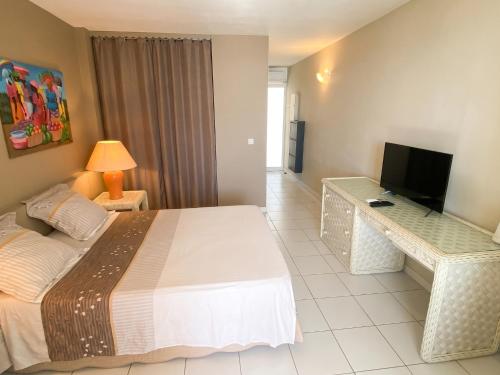 a bedroom with a large bed and a television at Studio confortable avec vue sur la mer in Le Gosier