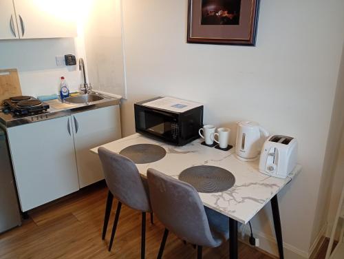 a small kitchen with a table with chairs and a microwave at Castle Walk Apartment in Stirling