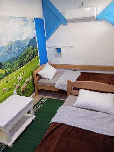 a room with two beds and a painting of a mountain at Apartman Retro 2 in Žepče