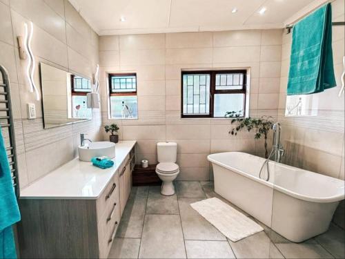 a bathroom with a tub and a toilet and a sink at Aviators Paradise Guest House in Mossel Bay