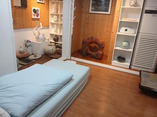 a room with a bed and shelves with vases at Art Residency in Busan