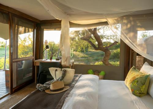 a bedroom with a bed with a hat on it at Onguma Tented Camp in Mokuti Lodge
