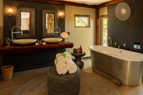 a bathroom with a tub and two sinks and towels at Onguma Tented Camp in Mokuti Lodge