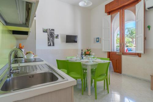 a kitchen with a sink and a table with green chairs at Villa Anny Fronte Mare in Avola