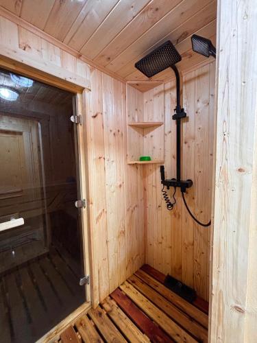 a small room with a shower in a wooden wall at GlamPark in Kurmenty