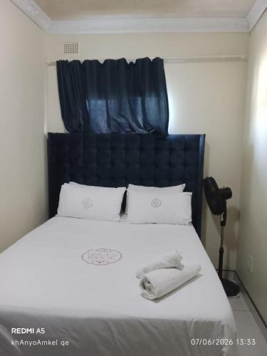 a bed with a black headboard and white sheets and pillows at LINGE'S LODGE EXTENSION in Lusikisiki