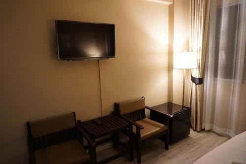 a room with two chairs and a television on the wall at Taris Art Hotel Phrae in Phrae