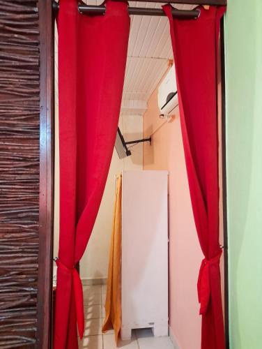 a room with red curtains and a refrigerator at Studio confortable à Capesterre-de-Marie-Galante - 20 m² in Capesterre