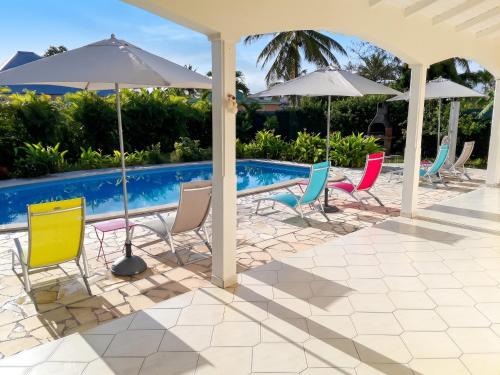 a group of chairs and umbrellas next to a pool at Appartement cosy à Sainte Rose / 50 m² / Piscine partagée in Diavet