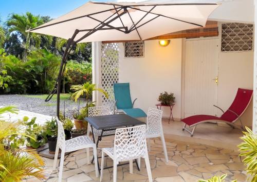 a patio with a table and chairs and an umbrella at Appartement cosy à Sainte Rose / 50 m² / Piscine partagée in Diavet