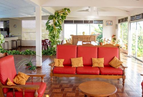 a living room with a red couch and a table at Maison spacieuse avec piscine privée à Le François in Le François