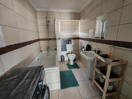 a bathroom with a sink and a toilet and a tub at Prince and Pooch Self Catering in Windhoek