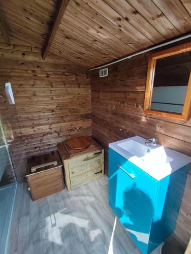 an inside view of a wooden bathroom with a sink at Le Nid des Prairies in La Chapelle-Engerbold
