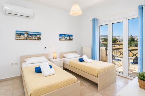 two beds in a room with a balcony at Hermione Villa in Gennadi