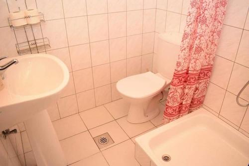 a white bathroom with a toilet and a sink at Andrea Apartman in Siófok